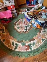 Full view of the round floral area rug with a pile floral design and multi-colored border, showing overall condition and colors.