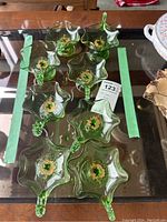 Top view of all 8 green art glass serving dishes showing their star-shaped wavy edge and central gold detailing.