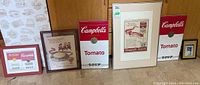 Full view of five framed vintage Campbell's Soup advertisements and prints including various soup labels and promotional ads.