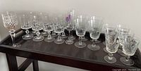 Whole set of 14 crystal and souvenir glasses on a dark tray with varied shapes and engraved patterns