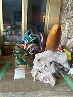 Various fish figurines including tropical fish on coral, wooden swordfish, dolphin, jade dolphin, and a wooden whale on a natural driftwood base.