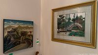 Two framed artworks hung side by side: left cloisonné enamel panel of the Great Wall, right fabric embroidery garden scene