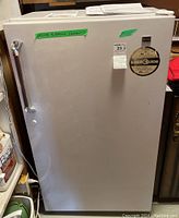 Front view of white Kenmore mini freezer showing chrome handle, energy guide label, and green tape for removing contents.