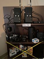 Shelf with two Takie Citizens band walkie talkies, vintage film cameras, lenses, and camera cases