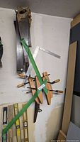 Hand saws, wooden clamps, aluminum framing square and spirit levels arranged against a wall