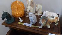 Group photo of all animal figurines and horse head bookends on wooden table showing ceramic and marble textures.
