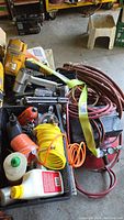 Overview of air tools, hoses, oil and paint sprayer accessories packed in basket next to compressor