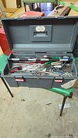 Full toolbox open with hand tools visible inside showing screwdrivers, wrenches, pliers, and other tools