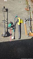 Full view of lot showing various yard tools including Stihl FS 85 trimmer with hedge attachment, yellow electric blower, Ryobi trimmer and others.
