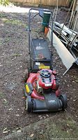 Full view of Craftsman Precision Plus lawn mower with black grass collection bag attached, red and black body, situated outdoors.