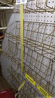Six gold-coloured metal racks with five sections each mounted on pegboard, measuring about 24x6 inches each.
