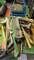 Photo showing a pile of assorted metalworking hand tools including wire brushes, hacksaw, flaring tool and protective glove.