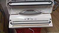 Open vacuum sealer showing sealing bar and control panel with mode buttons.