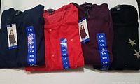 Four Buffalo David Bitton ladies long sleeve knit tops folded, showing color variety and size tags