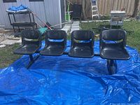 Front view of the 4-seat tandem bench with black molded seats on a blue tarp outdoors.