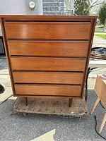 Front elevation view of dresser showing five full-width drawers with integrated pulls and tapered legs.