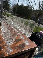View of all 14 crystal stemware glasses arranged in two rows showing the difference between liquor glasses and champagne flutes.