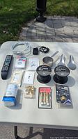 Photo showing all items arranged on table: remotes, cables, wire rolls, switch plates, hardware and kitchen spoons