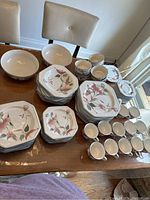 Full spread of Mikasa Octagon Silk Flowers dish set displayed on wooden table showing various plates, bowls, cups and saucers
