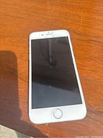 Full front photo of silver iPhone A1549 showing black screen with noticeable cracks on the top right corner and front white bezel.