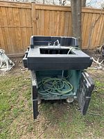 Front view of Cambro portable outdoor sink showing faucet, sink basin, hose coiled inside compartment with open doors, and wheels on base.