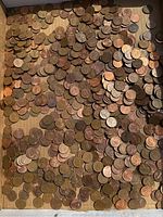 Wide view of the large collection of pennies spread out showing many copper and bronze coins.