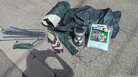 Photo includes green and purple trimmed tent fabric rolled up, tent poles, camping light, tent stakes, and Reliance water jug instruction packet.
