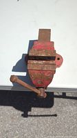 Top view of cast iron vintage benchtop vise showing flat jaws, handle, and red paint with wear and rust.
