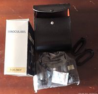 Photo showing 7x35 ZWCF binoculars accessories: original box, black carrying case, strap, lens caps, and cleaning cloth still in plastic bag