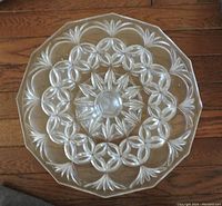 Top view of the clear crystal cake platter showing intricate cut pattern with interlocking circles and leaf motifs.