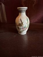 Porcelain miniature vase with bird and flowers on branch, light decorative band near rim.