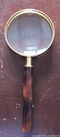Round magnifying glass with wooden handle on brown surface