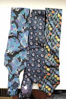 Three men's silk ties in blue tones with abstract, circular, and floral patterns