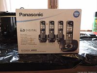 Photo of the boxed Panasonic KX-TG6434 phone system showing 4 handsets and base unit with answering machine features.