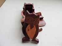 Wooden owl shaped jewelry puzzle box with hinged cover open, showing storage cavity inside
