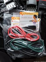 Two GoldenEarth Pilates Yoga resistance bands and instructional booklet sealed in plastic bag.