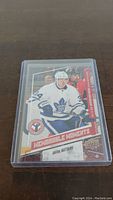 Front of Auston Matthews rookie card in protective case showing player in white Toronto Maple Leafs jersey.