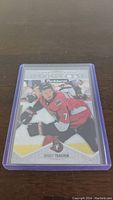 Front of Brady Tkachuk rookie card from 2018-19 Parkhurst, featuring player in Ottawa Senators uniform skating on ice, card in purple protective case.