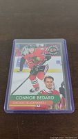 Front side of Connor Bedard Chicago Blackhawks hockey trading card showing in-game action photo and portrait