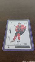 Front view of Connor Bedard rookie hockey card in protective plastic sleeve showing player in Chicago Blackhawks uniform.