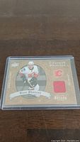 Front of Dion Phaneuf jersey card showing image, team logo, player name, and embedded red jersey piece.