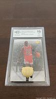 Michael Jordan basketball card graded BCCG 10 encased in protective slab, showing front with red Bulls uniform and gold embossed emblem.