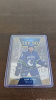 Front of Quinn Hughes 2019-20 Upper Deck Allure Top 50 Rookie Hockey Card in protective sleeve showing player image and design.