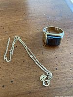 Overview of signet ring and tangled chain on wood surface