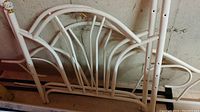 White metal day bed frame components showing curved rods and chipped paint.