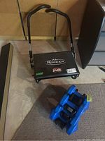 Ab Rocker exerciser with padded seat and dual handles for abdominal workouts, positioned on a basement floor near carpet.