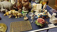 Wide view of ceramic figurines, cookie jar, paperweight and other items on table