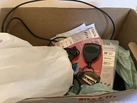 Box with multiple Key Bak self-retracting key reels, packaging inserts, and some charging cable plugs.