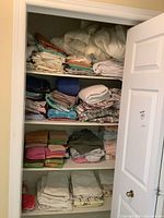 View of the closet shelves stacked with folded towels, face cloths, and bed linens.