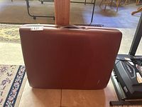 Photo of folded and closed vinyl massage table showing its brown exterior surface and visible wear.